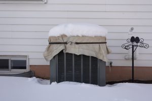 Outdoor hvac air conditioning units idling during the winter with snow on top of the fans